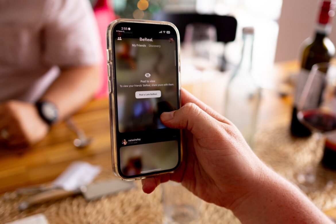 A man's hand holding an iPhone, symbolizing the digital age and social media engagement.